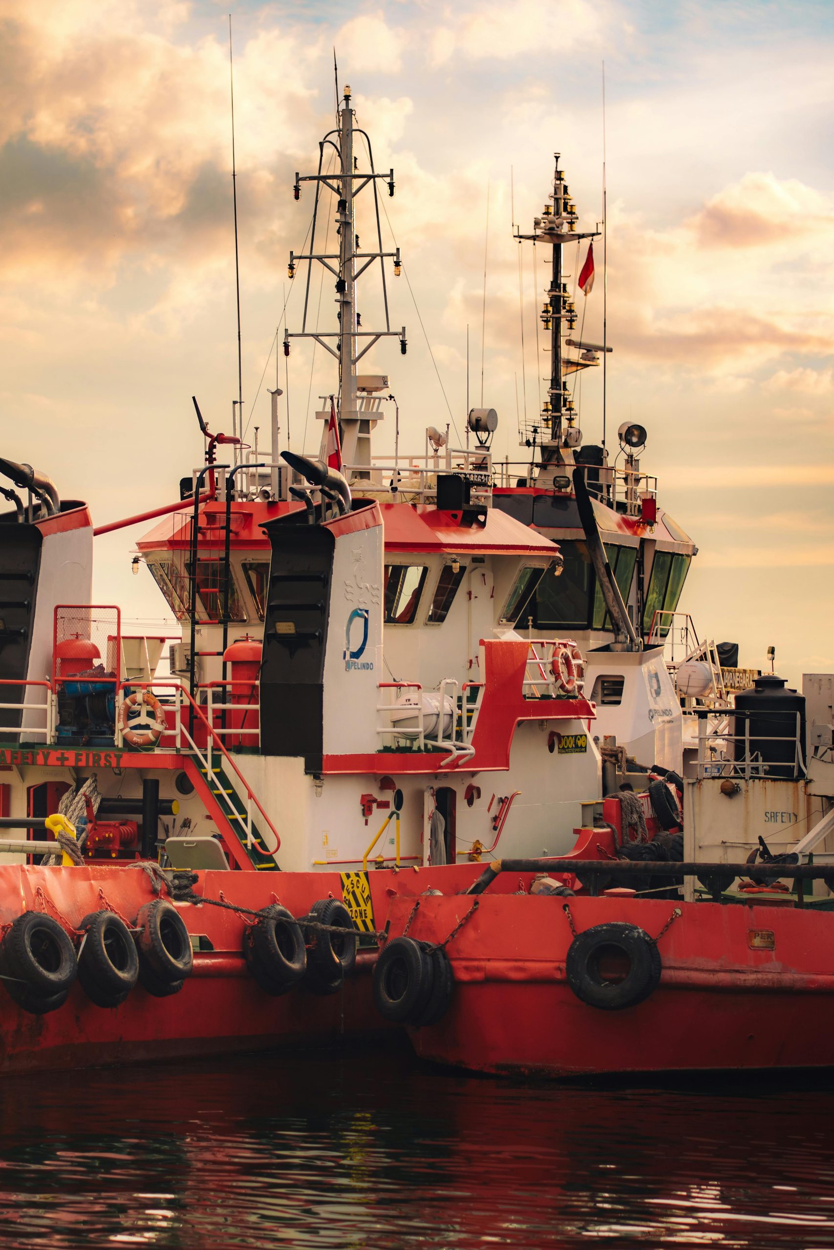 Vibrant sunset view of tugboats docked in Makassar Harbor, South Sulawesi, Indonesia.